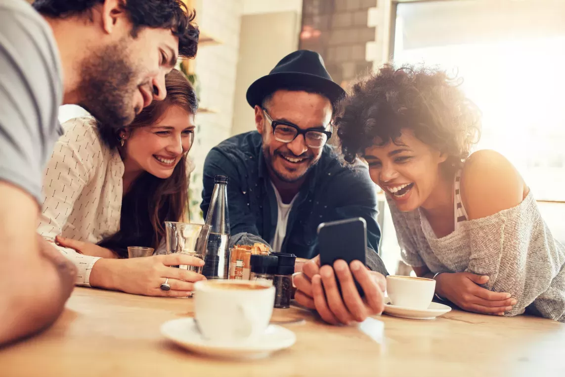 A group of friends watch a video at a table
