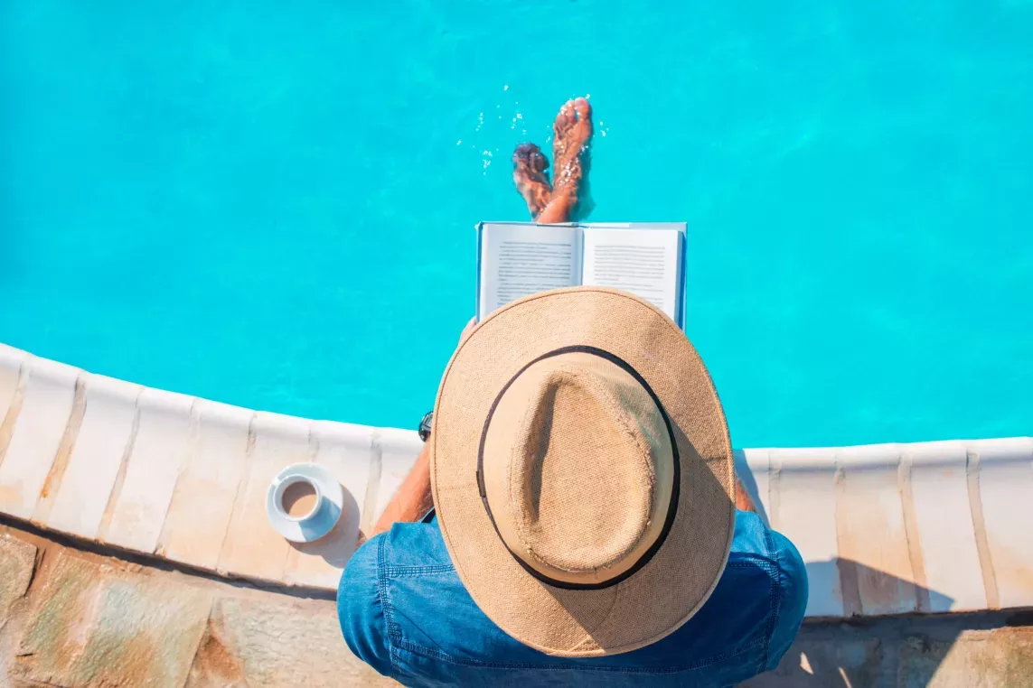 Person sits and reads by the pool