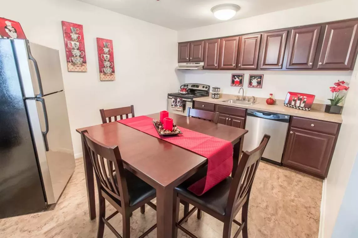 Modern kitchen and dining area at Silver Lake Manor Apartments, featuring dark wood cabinetry, stainless steel appliances, and stylish red decor accents for a warm and inviting atmosphere.