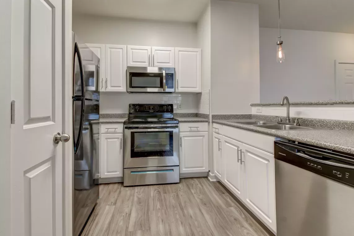 Modern kitchen with stainless steel appliances, granite countertops, and white cabinetry at The Saulet Apartments in New Orleans, LA.
