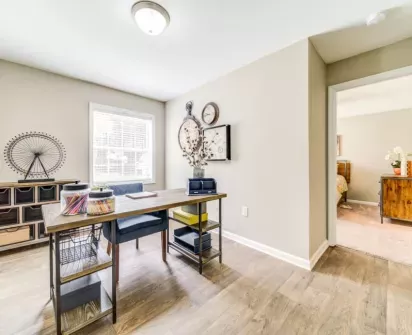  Bright home office space featuring a large desk, modern decor, and ample natural light from a nearby window, creating a productive and stylish work environment.