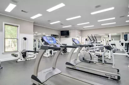 A well-equipped fitness center featuring treadmills, strength training machines, and ample space for a complete workout in a bright, modern setting.
