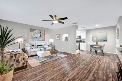 Open-concept living space with stylish wood flooring, a cozy living room setup, dining area, and modern kitchen, complemented by neutral tones and natural lighting for a warm and inviting atmosphere.