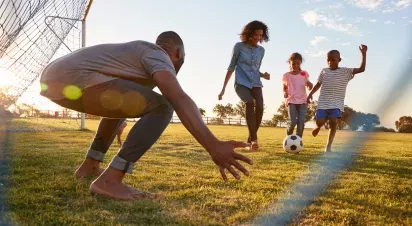 Family enjoying a lively soccer game in a sunlit park, highlighting community spirit, outdoor fun, and quality family time.