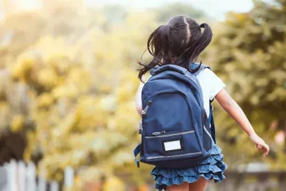 A young girl joyfully walking with a backpack, her pigtails bouncing as she heads off on an adventure. The warm and vibrant background adds a playful and carefree feeling to the moment.