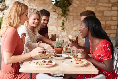 A group of friends enjoying a meal together at a cozy restaurant, sharing delicious food and laughter in a vibrant, relaxed atmosphere. The warm ambiance and good company make for an unforgettable dining experience. Perfect for creating lasting memories with those you care about.