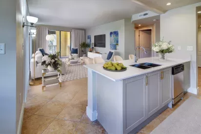 A modern open-concept living space with a spacious kitchen island, bar stools, and cozy seating area featuring bright, neutral decor.