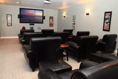 A stylish home theater room with black leather recliners, a large screen, and movie-themed wall decor for a cinema-like experience.