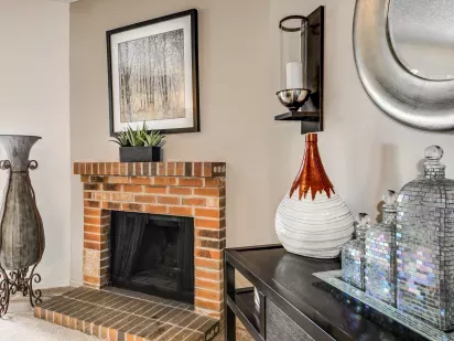 A cozy corner with a brick fireplace, decorative artwork, and modern accent pieces.