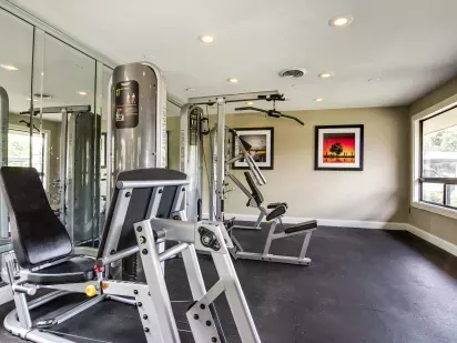 A well-lit fitness center with modern exercise equipment and mirrored walls.