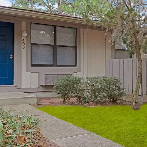 Charming single-story apartment buildings with vibrant landscaping, bright blue doors, and private entrances, reflecting the inviting and well-maintained community of Bridgepoint Apartments.