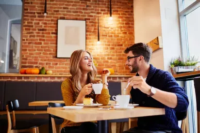 Couple having drinks at a warm cafe with a brick wall and natural light.