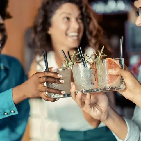A group of friends toasting with stylish cocktails garnished with fresh herbs, enjoying a lively and social atmosphere.
