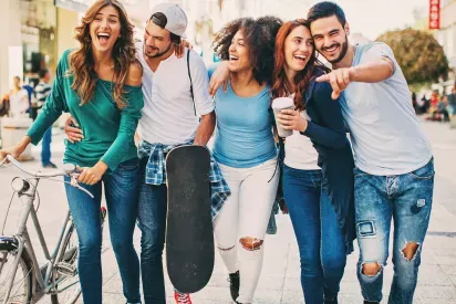 Group of friends laughing and walking down sidewalk