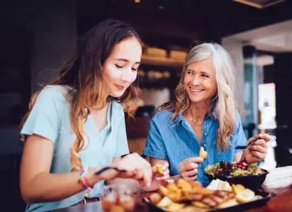 Two women enjoying a meal together at a cozy restaurant, smiling and engaging in conversation. This image highlights the vibrant dining and social opportunities near Broadview Oaks Apartments.