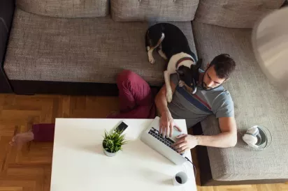 Man working on laptop while sitting with dog