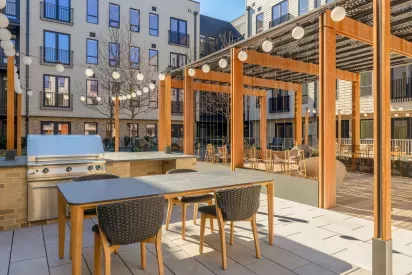 Stylish outdoor lounge with modern furniture and community grilling stations, perfect for social gatherings.