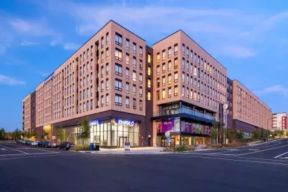 The Edmund Apartments building at dusk, showcasing contemporary architecture, retail spaces, and well-lit surroundings for an inviting urban living experience.
