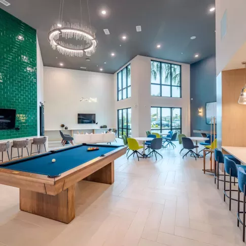 Image 6: Luxurious game room with a billiards table, cozy seating areas, and contemporary lighting at Tropia Wellen Park Apartments.