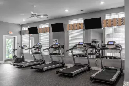 A well-equipped fitness center with multiple treadmills, exercise bikes, and a wall of windows letting in natural light.