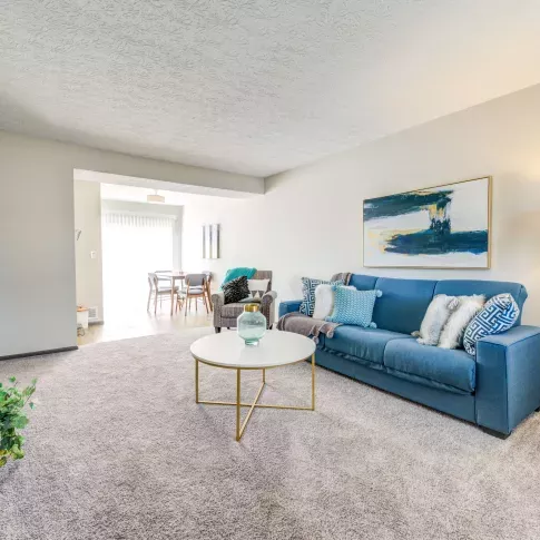 Comfortable living room with a navy sectional couch, decorative pillows, and stylish decor at Worthington Meadows Apartments.