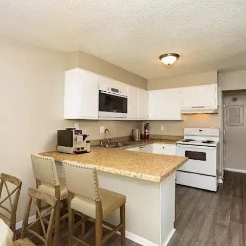A cozy kitchen with white cabinetry, a breakfast bar with seating, and modern appliances, seamlessly connecting to the dining area.