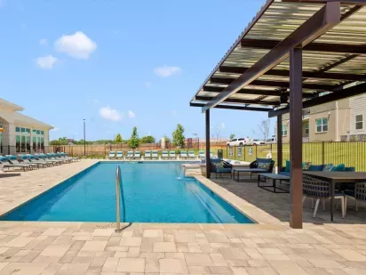 Outdoor swimming pool with lounge chairs and a shaded seating area.