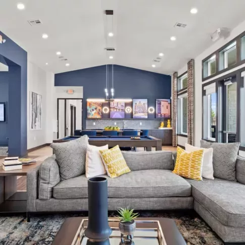 A spacious clubhouse with a contemporary sectional sofa, vibrant decor, and pool table, designed for social gatherings and relaxation.