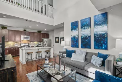 A spacious living area with a kitchen in the background, showcasing an open-concept design at Arrabella Apartments.