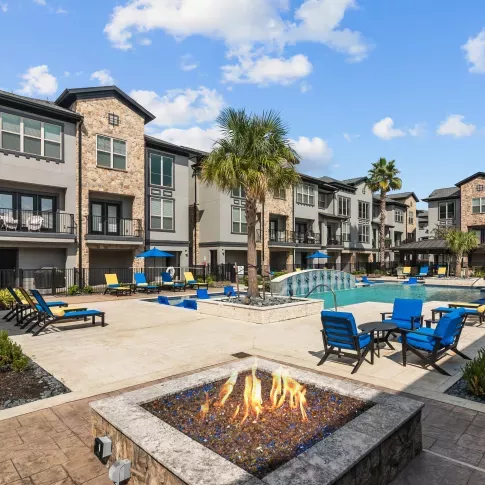 A cozy outdoor fire pit with modern seating, adjacent to the pool area, creating a perfect evening ambiance.