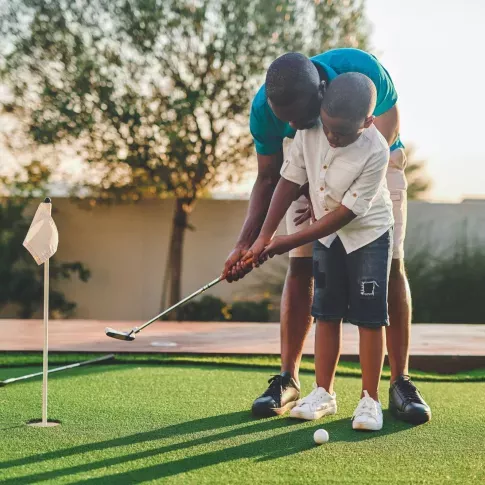 A man teaches his son how to golf