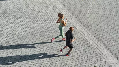 Two people running on pavement