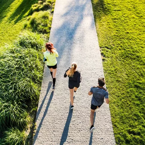 Three people jogging through a park