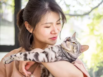Woman holding a striped cat