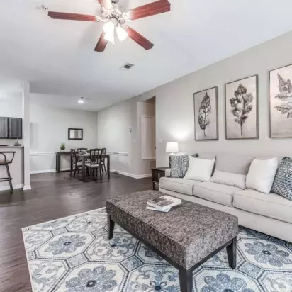 Open-concept living room with a cozy beige sofa, accent chairs, and contemporary wall art, offering a welcoming atmosphere.
