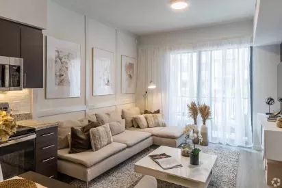 Modern living room interior at Pine Ridge Luxury Apartments, featuring a cozy sectional sofa, soft lighting, and elegant wall decor.