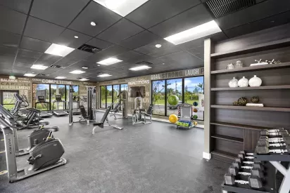 A spacious gym with state-of-the-art exercise equipment and motivational wall graphics, designed for an active lifestyle at Pine Ridge Luxury Apartments.
