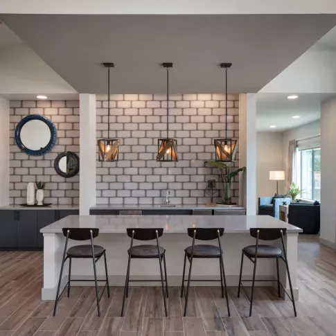A stylish resident lounge with a sleek bar area, pendant lighting, and contemporary decor offers a sophisticated space for socializing and relaxation.