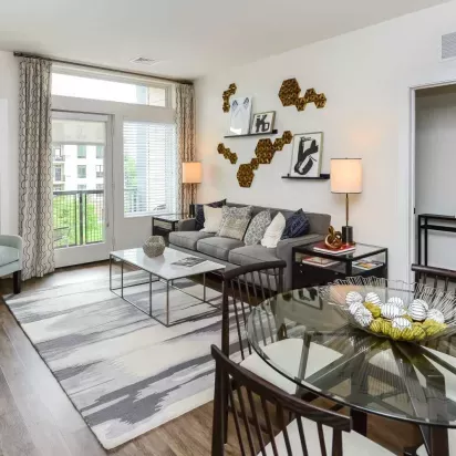 Contemporary living room featuring a gray sofa, modern wall art, and large windows leading to a private balcony with natural light.