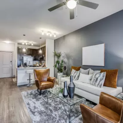 A cozy living room with a white couch, leather armchairs, and a glass coffee table.
