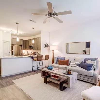 Open-concept living area with a cozy seating arrangement and a view of the contemporary kitchen at The Emerson at Forney.