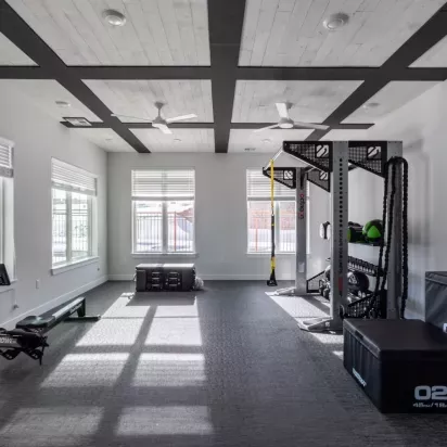 Fitness room showcasing a functional training rig, rowing machine, and ample floor space for diverse workout routines.
