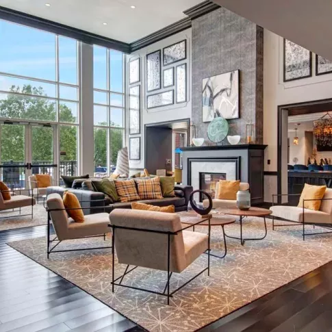 An elegant resident lounge with floor-to-ceiling windows, a cozy seating area, and a modern fireplace.