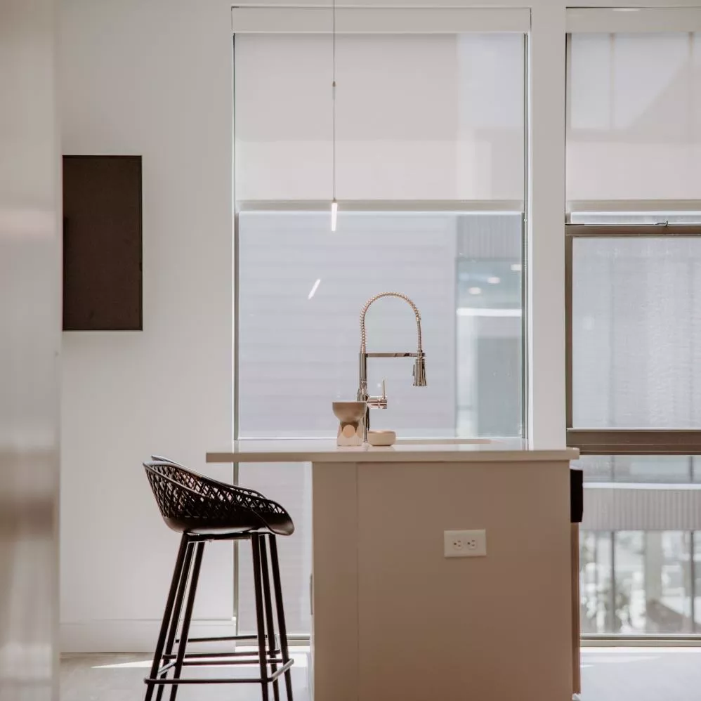 A modern kitchen at Industry Columbus Apartments featuring white cabinetry, stainless steel appliances, and a sleek island with bar seating.