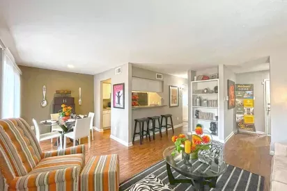 An open-concept living and dining area with hardwood-style flooring, built-in shelving, and chic furnishings.