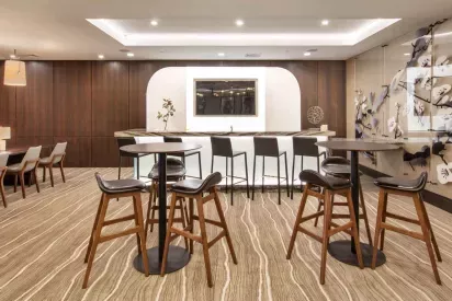 A stylish resident lounge with high-top seating, a built-in bar, and modern lighting.