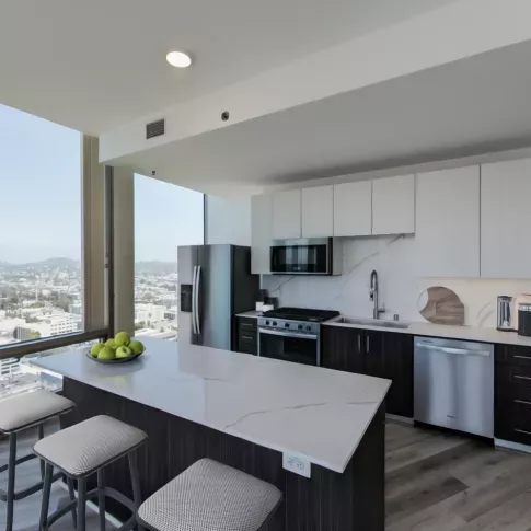 Spacious kitchen and dining area in Nari Koreatown penthouse with barstools at a large quartz island and floor-to-ceiling windows