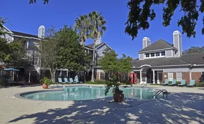 Gated swimming pool surrounded by lush landscaping and lounge seating at Gates at Citiplace apartments