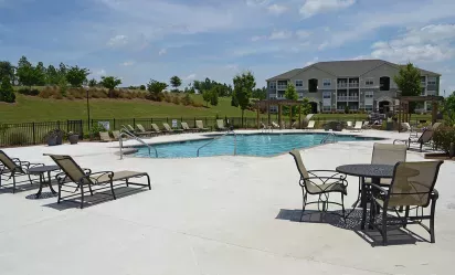Poolside seating area with lounge chairs and tables, overlooking the swimming pool and landscaped grounds.