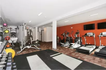 Modern gym at One23 Apartments featuring treadmills, elliptical machines, and weight equipment